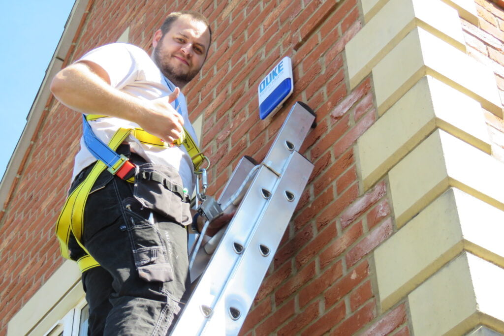 Man on a latter with thumps up after installing intruder / Burglar home security system