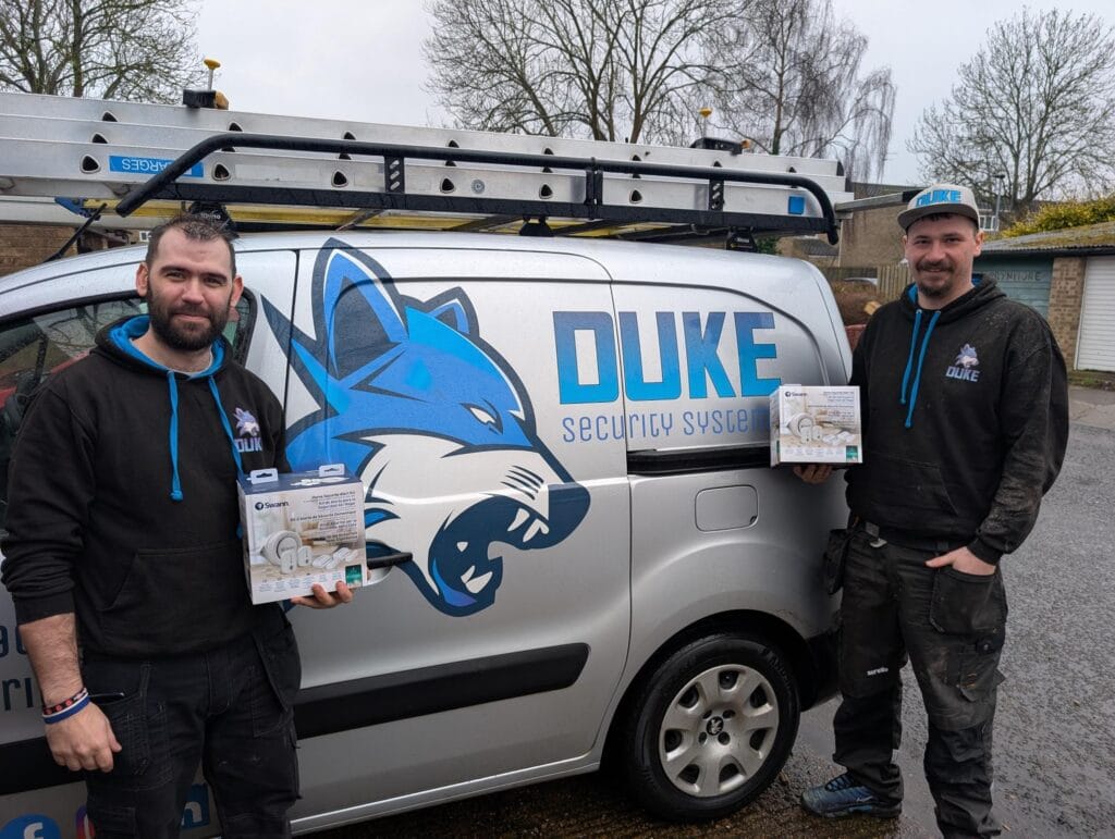 Duke Security engineers in front of van holding Swann CCTV alarm kit.
