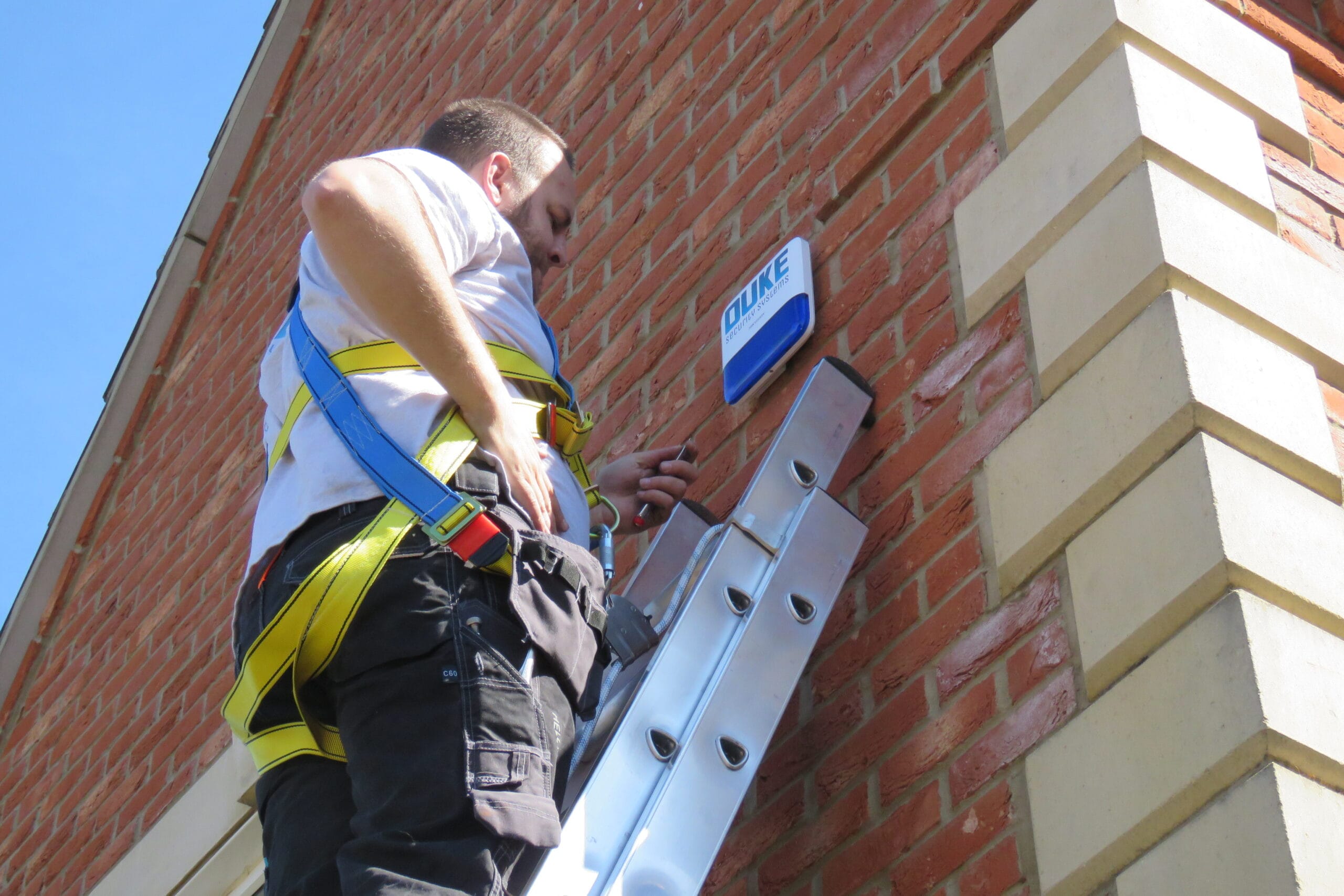 External alarm sounder installation on brick wall by Duke Security Systems engineer, Peterborough